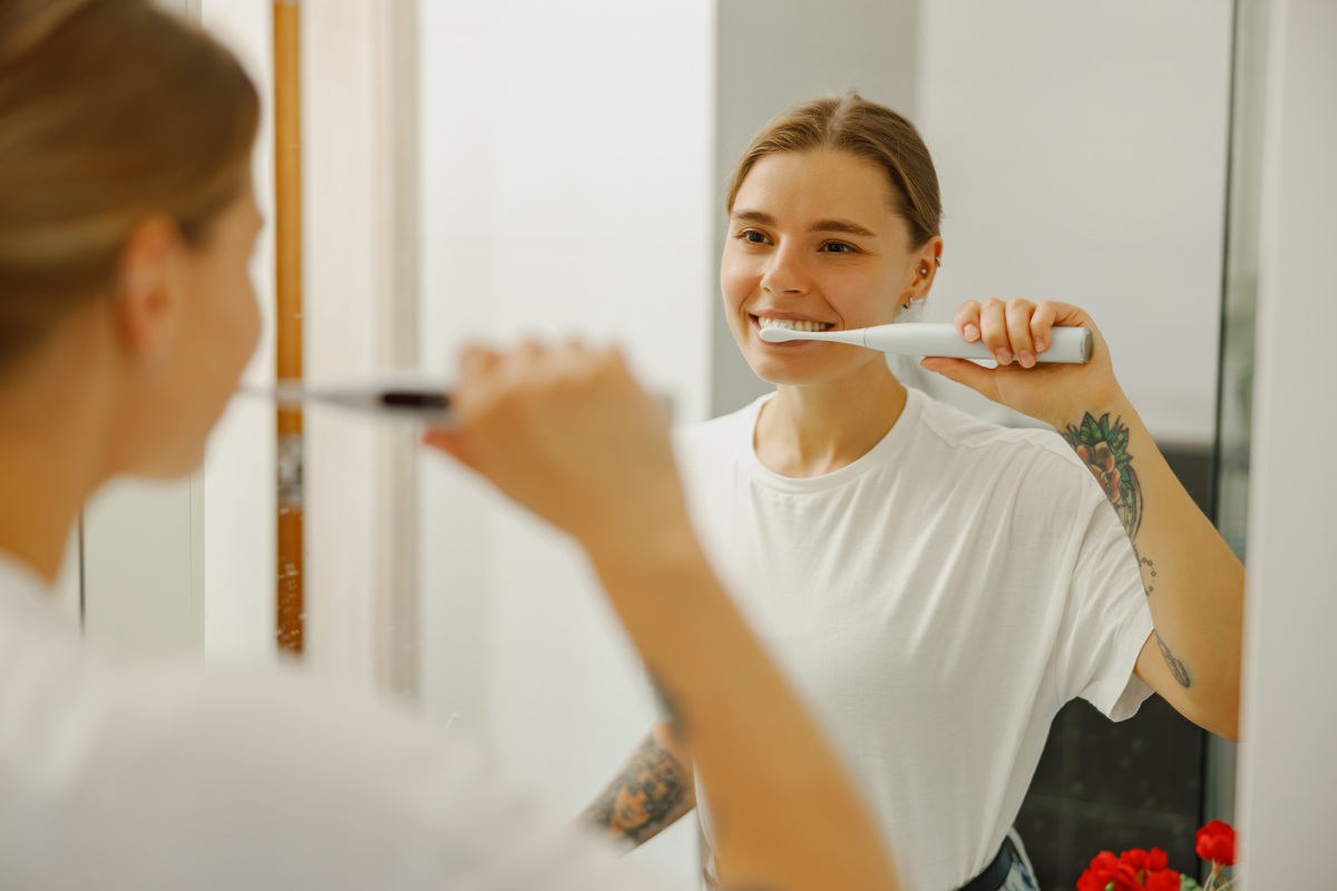 Woman brushing teeth with electric toothbrush