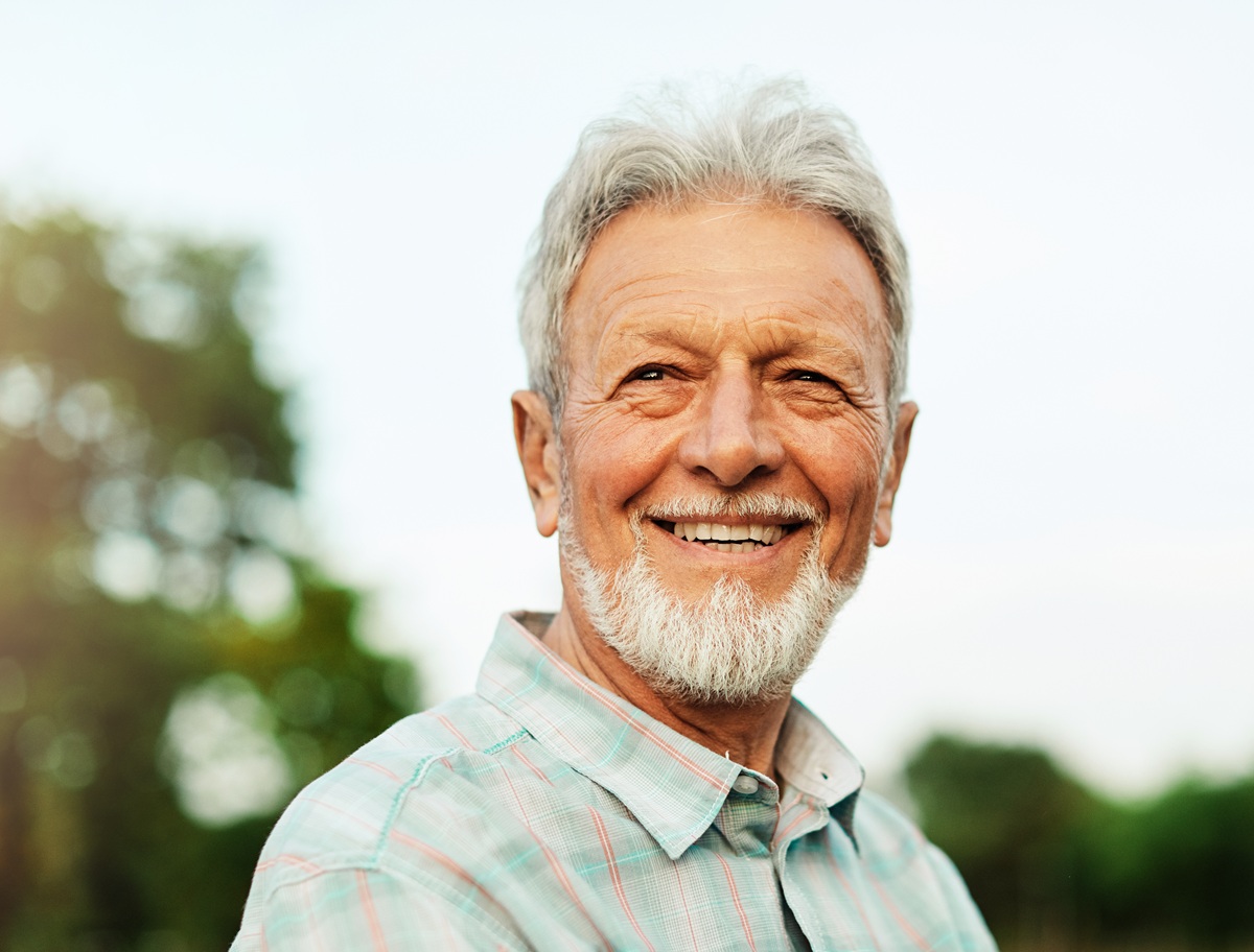 Older adult smiling after tooth replacement